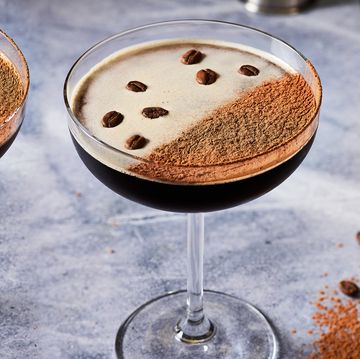 espresso martini in a coupe glass topped with espresso powder and coffee beans