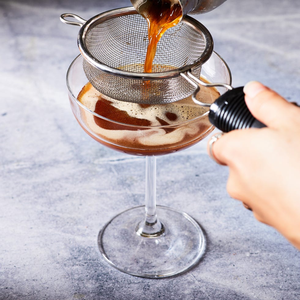espresso martini in a coupe glass topped with espresso powder and coffee beans