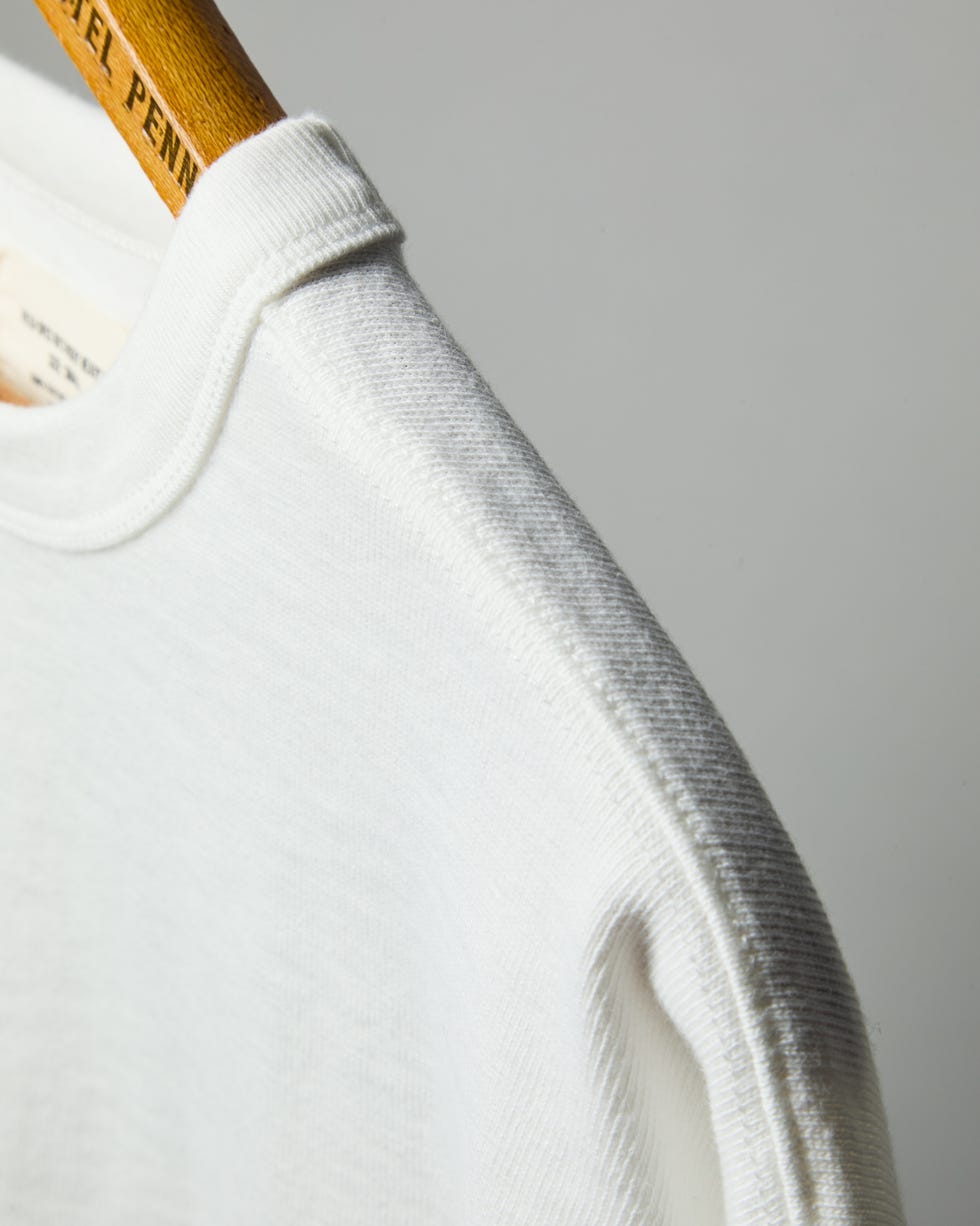una camiseta blanca en una percha de madera