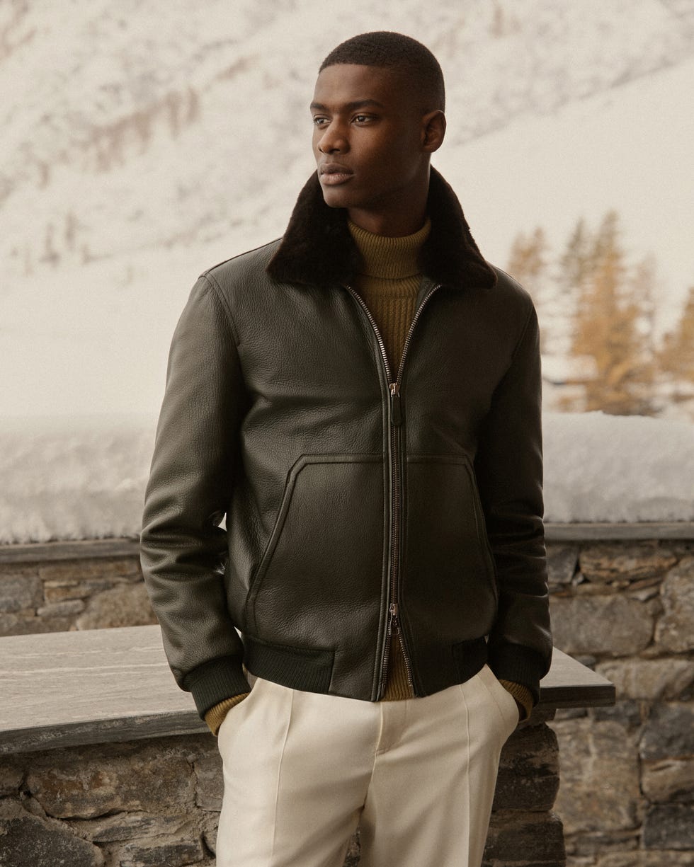 a person wearing a stylish leather jacket and lightcolored pants in a snowy landscape