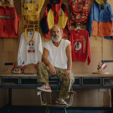 a person sitting on a stool in front of a store with a lot of clothes