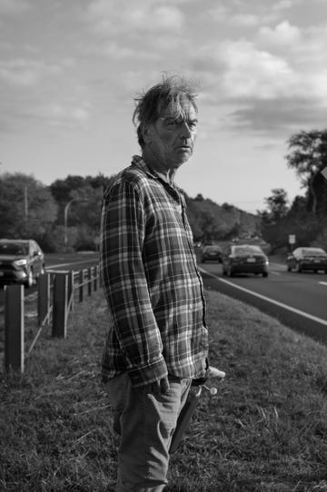 a person standing beside a road with vehicles in the background