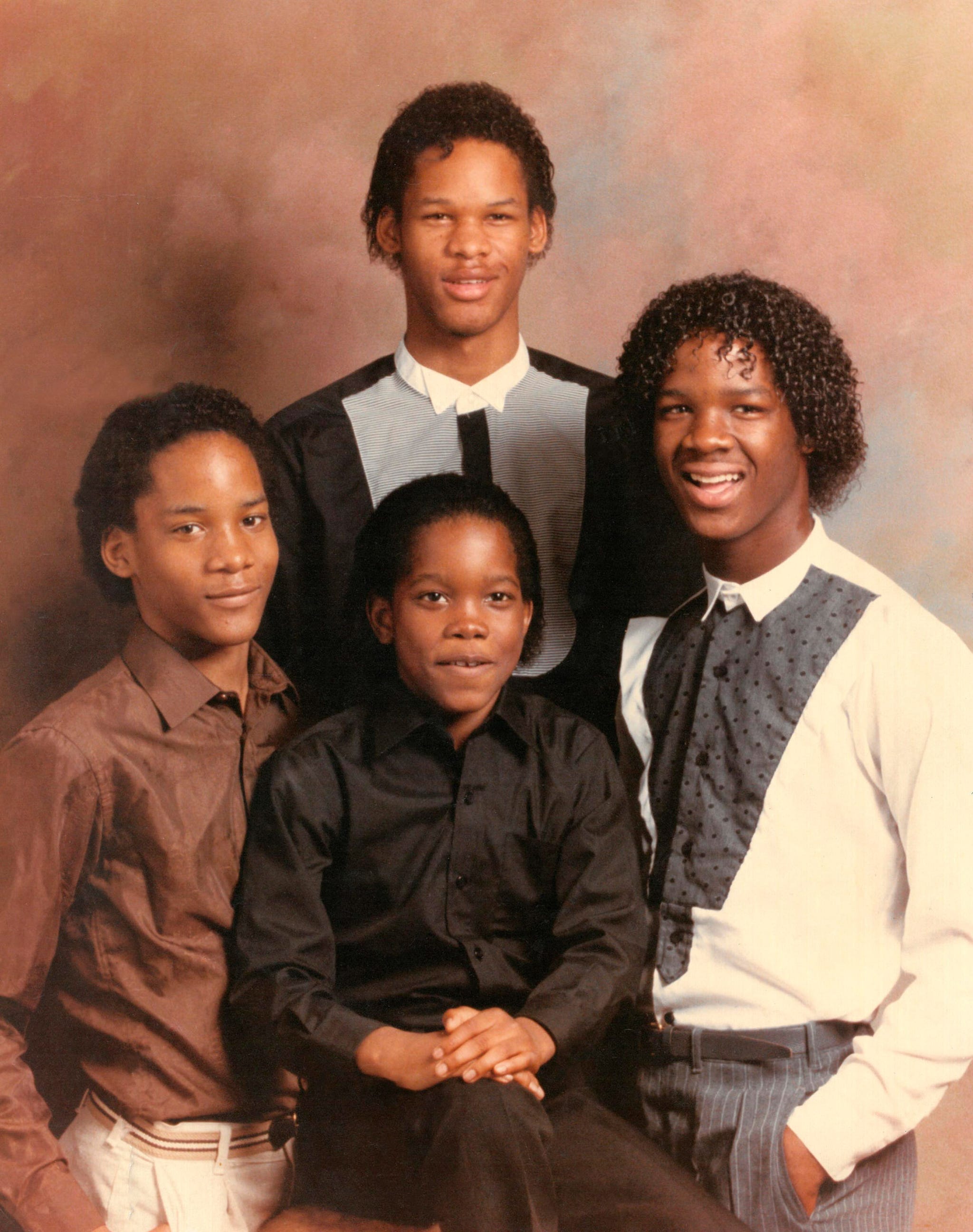 group of four individuals posed together with obscured faces dressed in formal attire