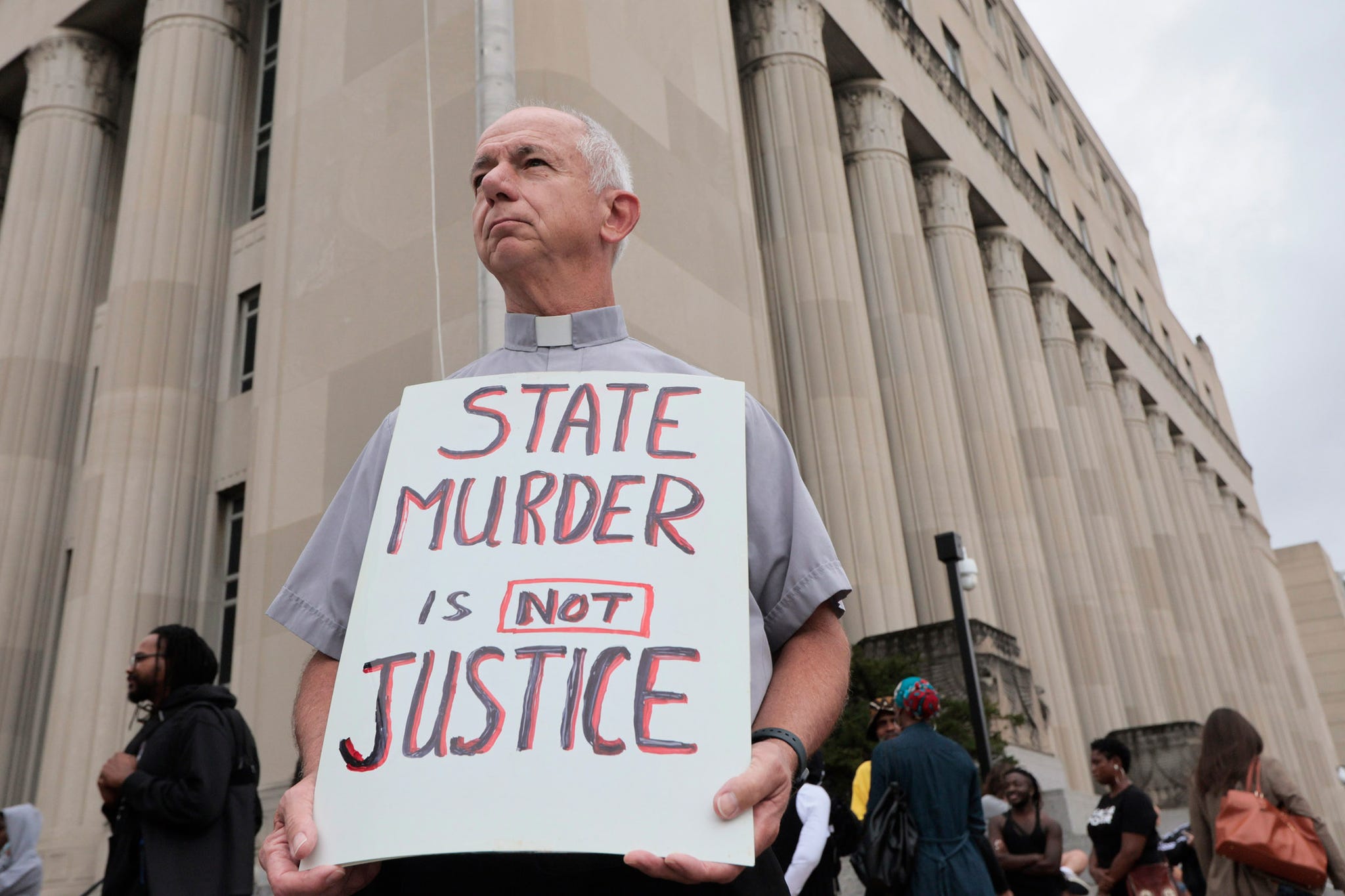 deacon dave billips, with the office of peace and justice with the st louis archdiocese, holds a sign as he stands with protesters holding space to halt the execution of marcellus williams on tuesday, sept 24, 2024, outside the carnahan courthouse in st louis laurie skrivanst louis post dispatch via ap