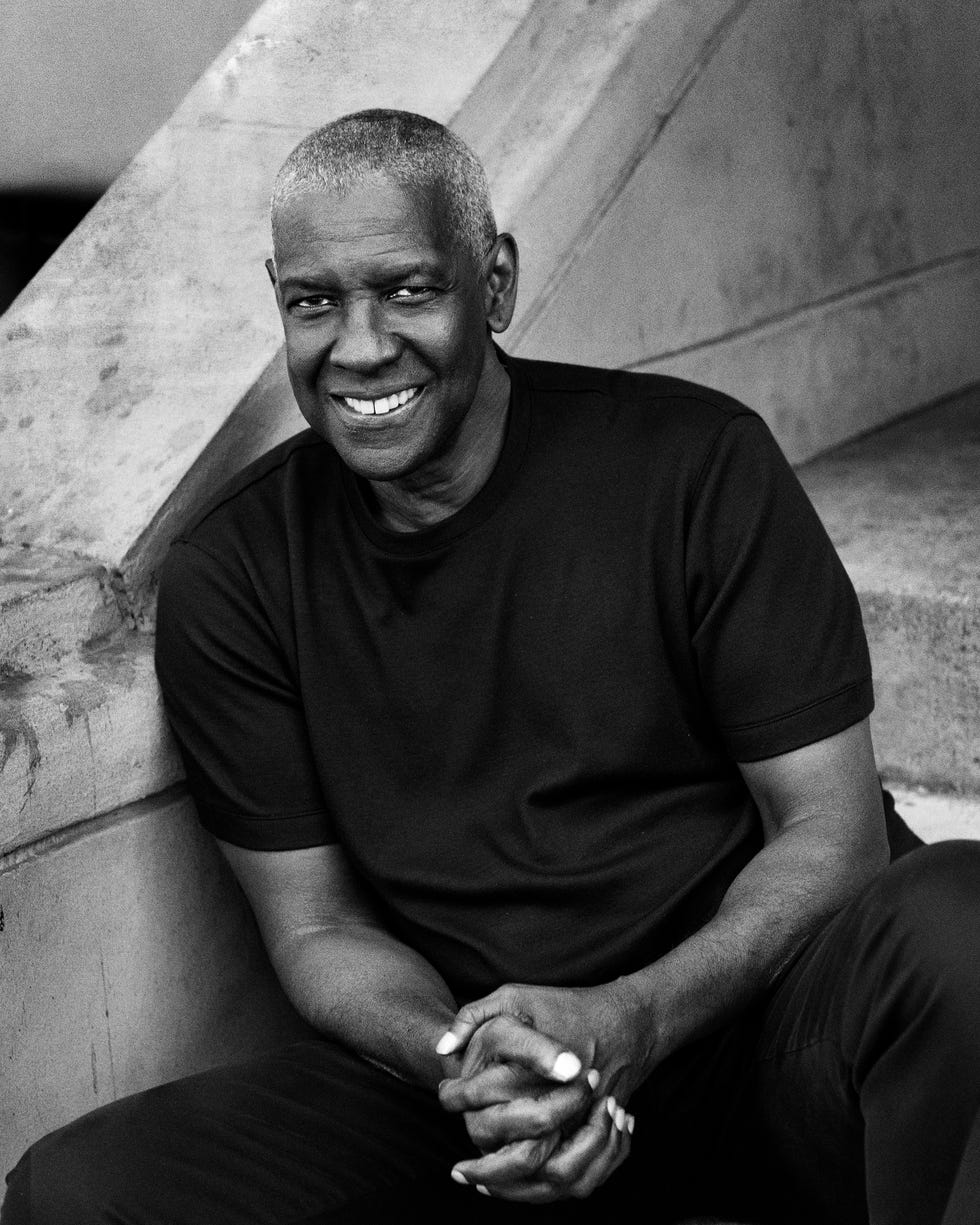 a person sitting on the ground with hands clasped wearing a black shirt