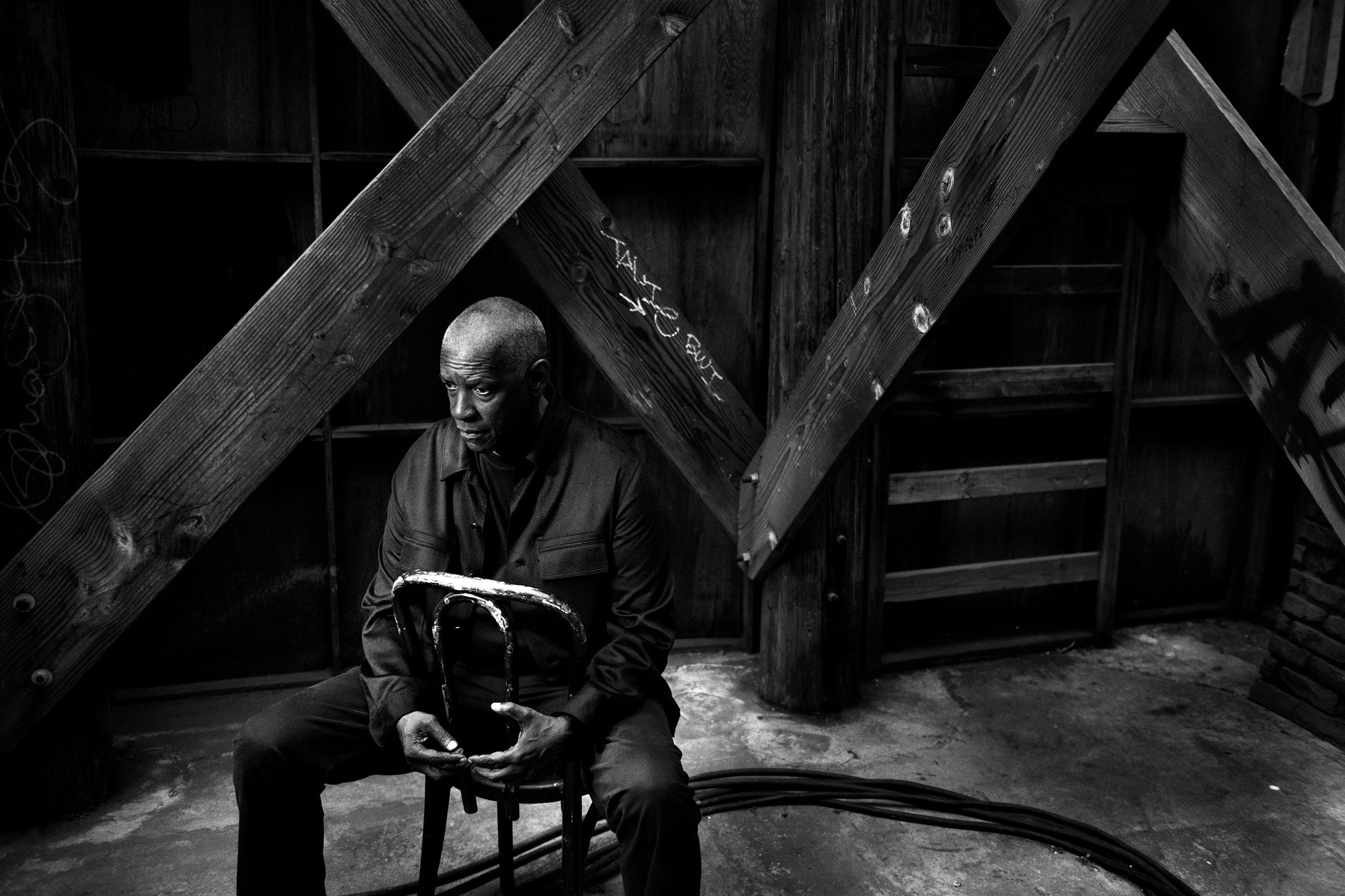 man seated on a stool in a dimly lit rustic environment