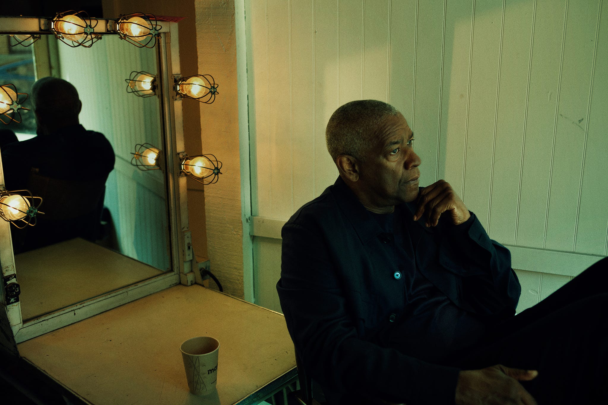 a person sitting in a dimly lit room next to a mirror with lights