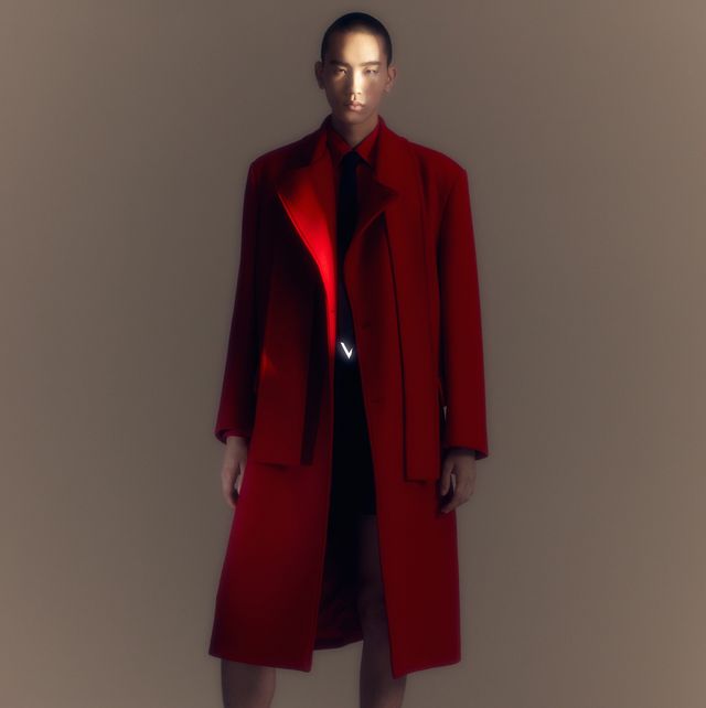 a mannequin wearing a red coat and black shoes from valentino