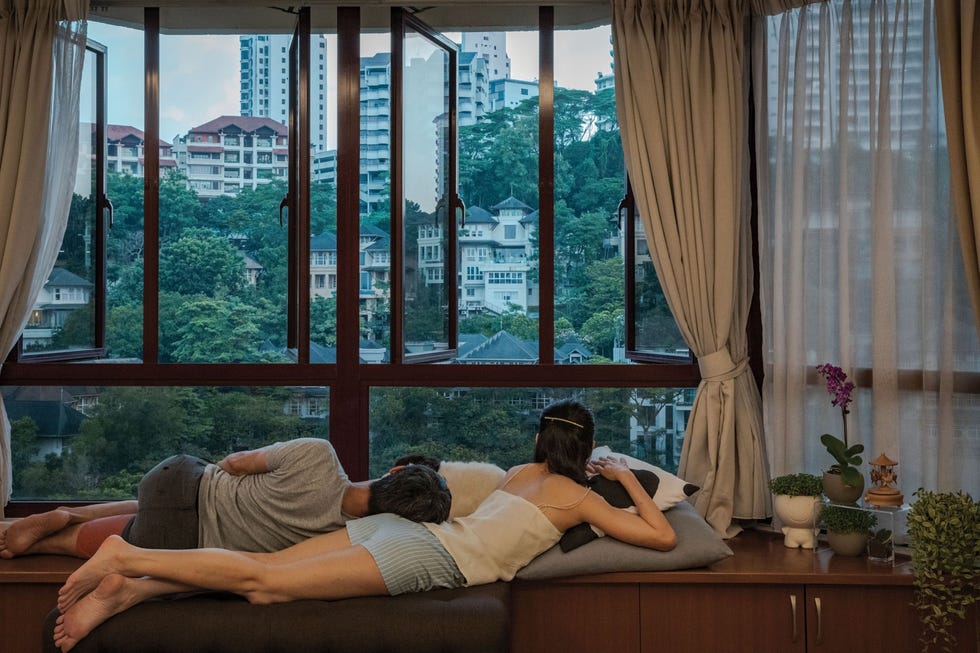 Kuala Lumpur, Malaysia KUALA LUMPUR MALEISIFotograaf Ian Teh reist voor zijn werk de halve wereld rond maar door de pandemie was hij gedwongen thuis te blijven bij zijn vrouw Chloe Lim in Kuala Lumpur Maleisi Mijn partner en ik zijn blij dat onze beide families veilig en wel zijn zegt hij De pandemie heeft ons de gelegenheid geboden om virtueel meer met onze dierbaren op te trekken Dit zelfportret van het stel nam hij op een van hun favoriete plekjes in het appartement dat uitkijkt op naburige huizen en groenruimten Het is hier vredig zegt hij