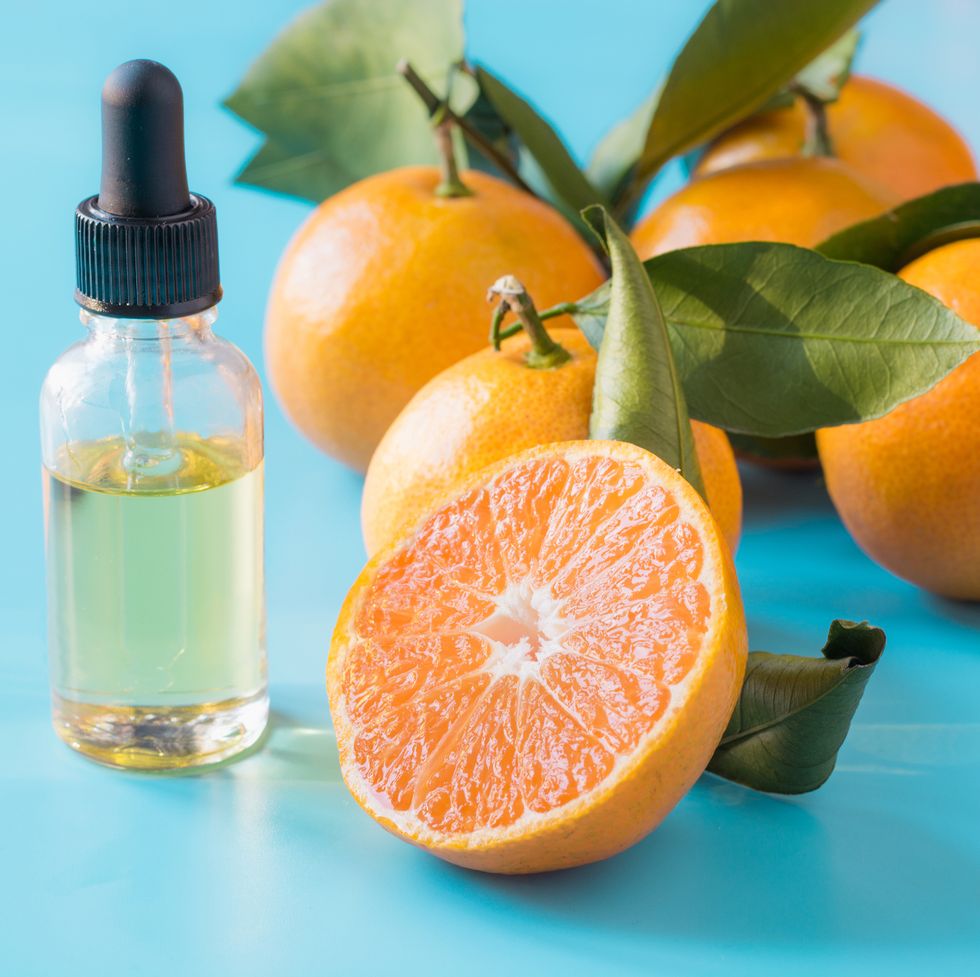Essential oil of orange mandarin in glass bottle over pastel blue background. Skincare concept.