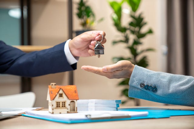 estate agent giving house keys to woman and sign agreement in office
