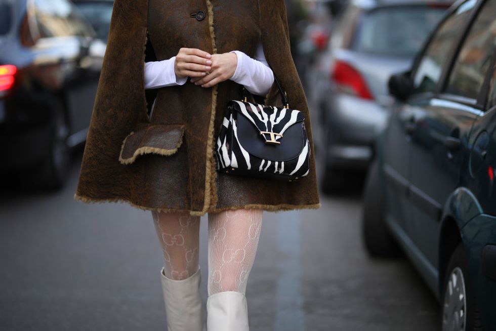 chica en la semana de la moda en milán con medias y botas blancas y bolso de cebra