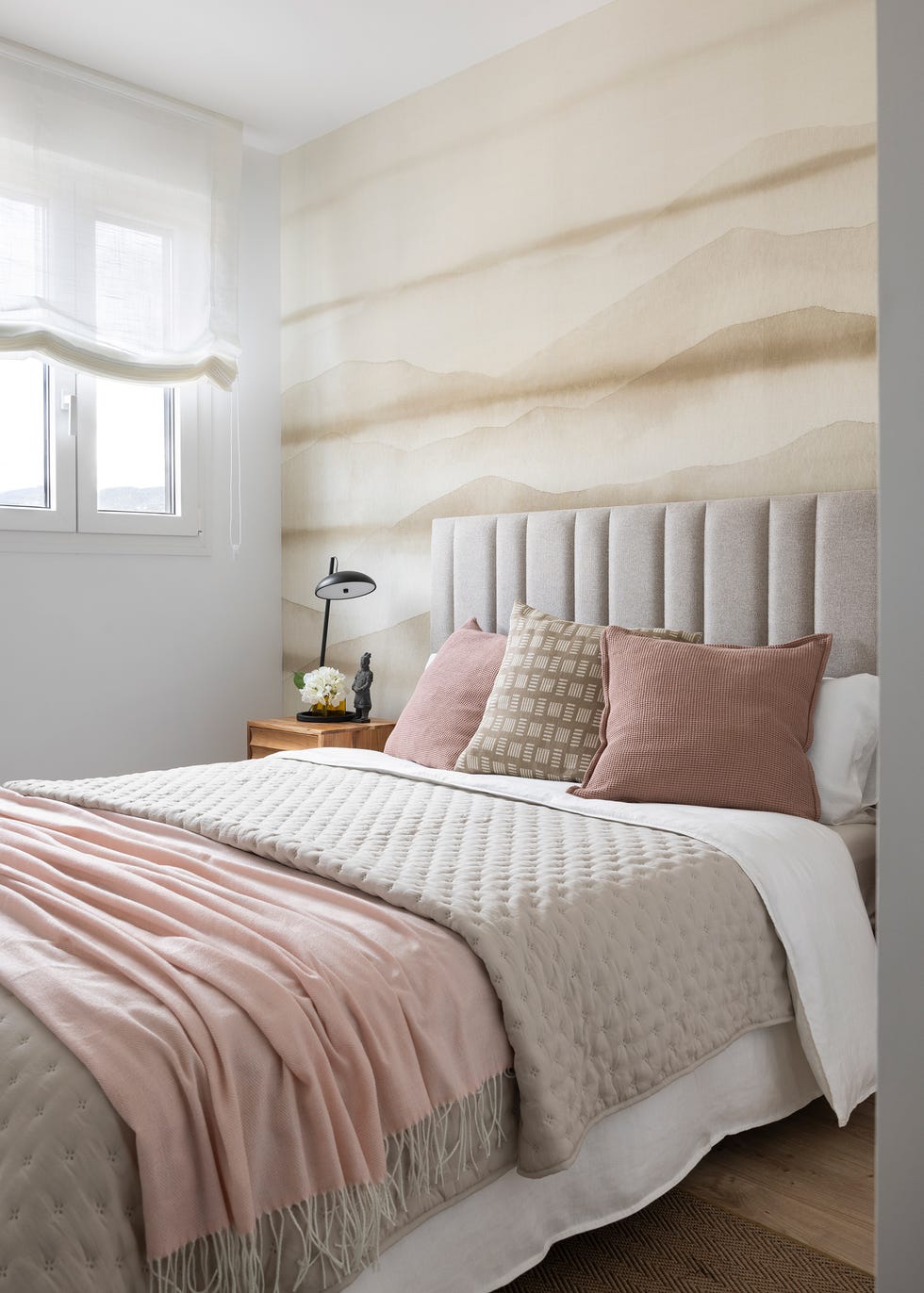cama con cabecero beige acolchado y papel pintado con motivos abstractos