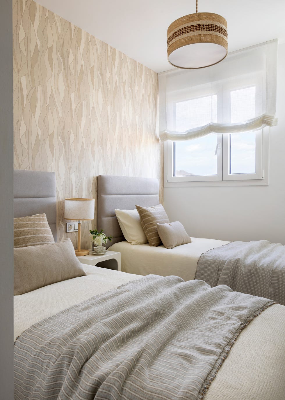 habitación con dos camas con cabeceros acolchados y papel pintado con motivos abstractos