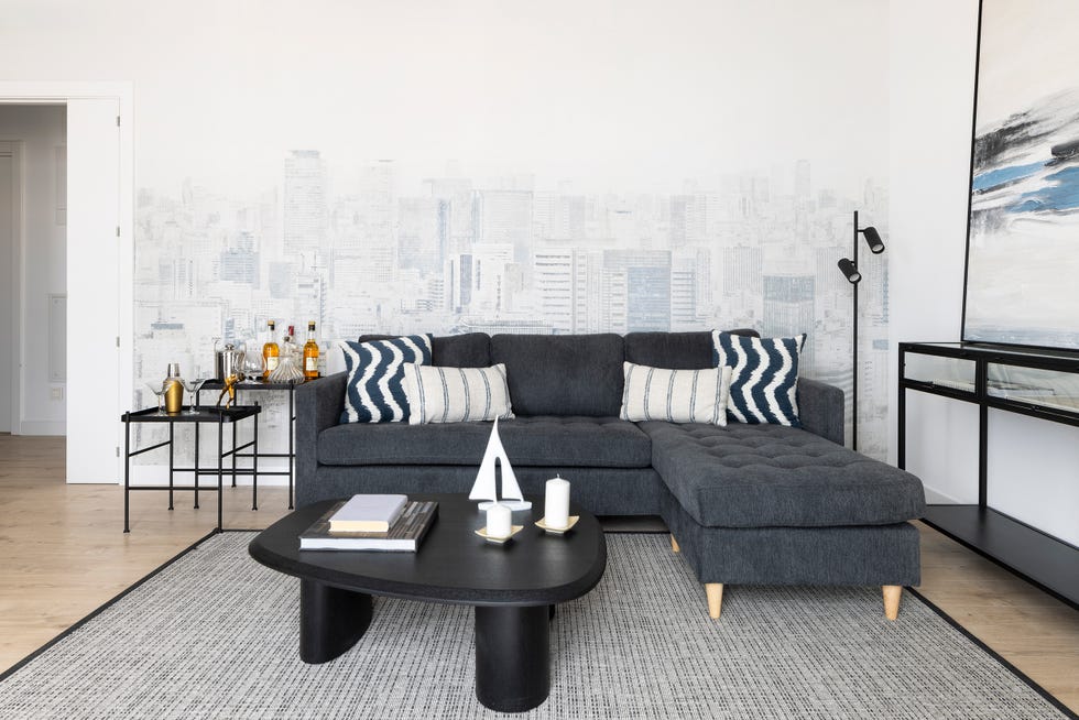 sofá con chaiselongue gris y papel pintado con dibujos de edificios