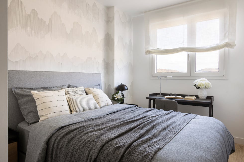 cama con cabecero gris, pared con papel pintado y escritorio negro