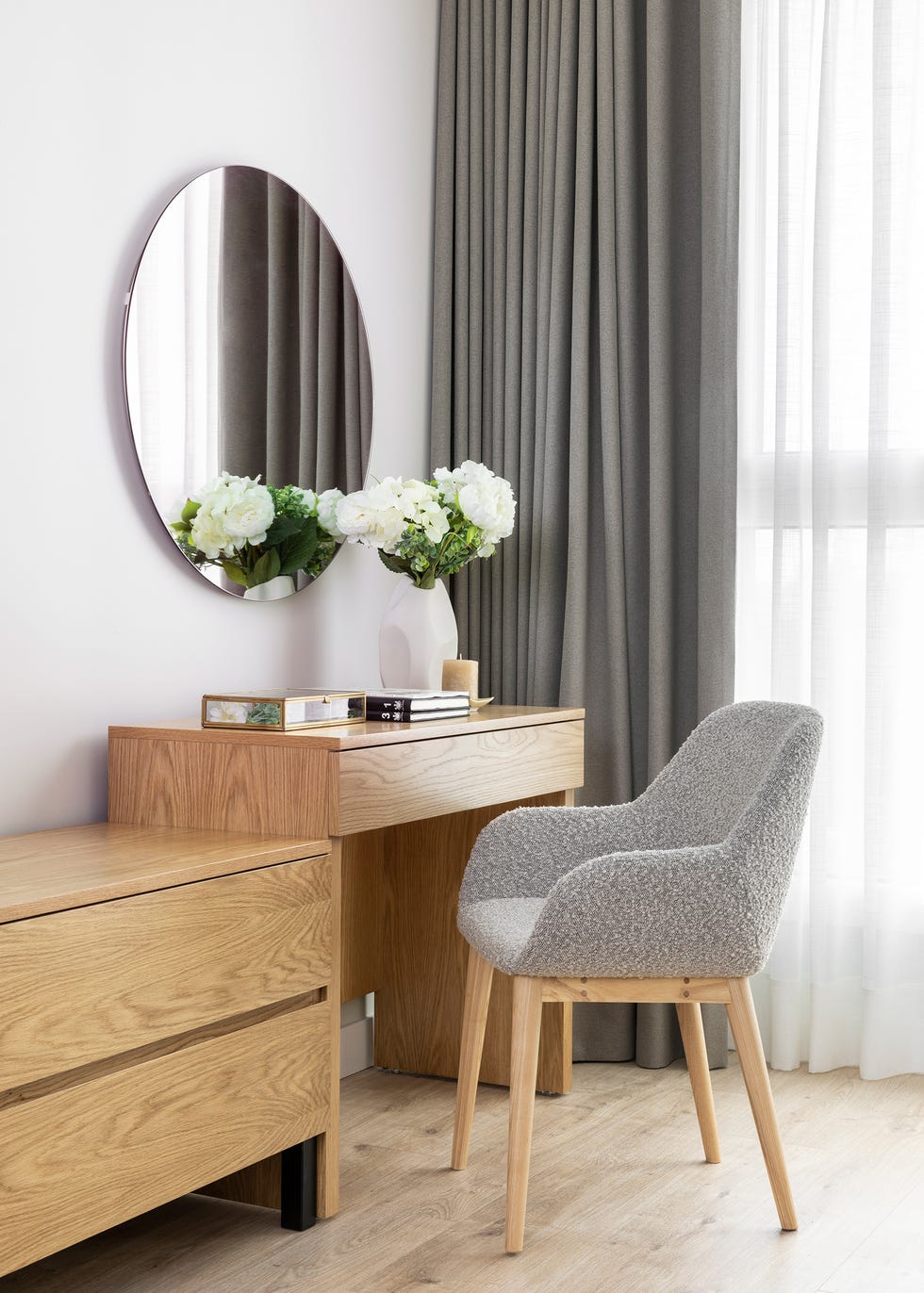 escritorio de madera, espejo redondo y silla con tapizado bouclé
