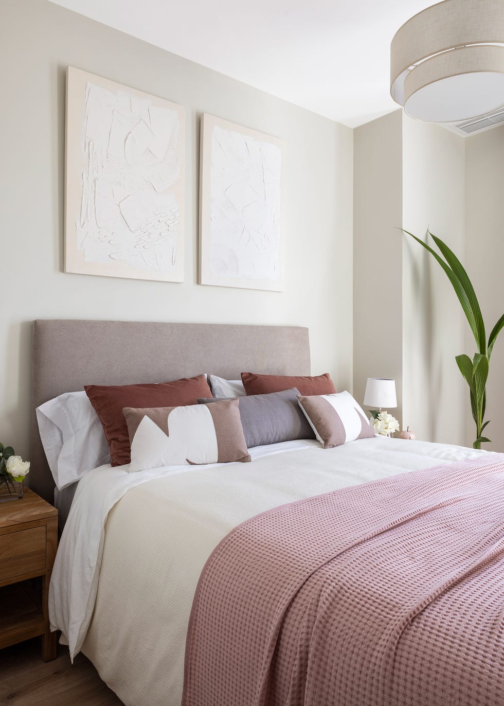 cama con cabecero tapizado beige y dos cuadros en la pared