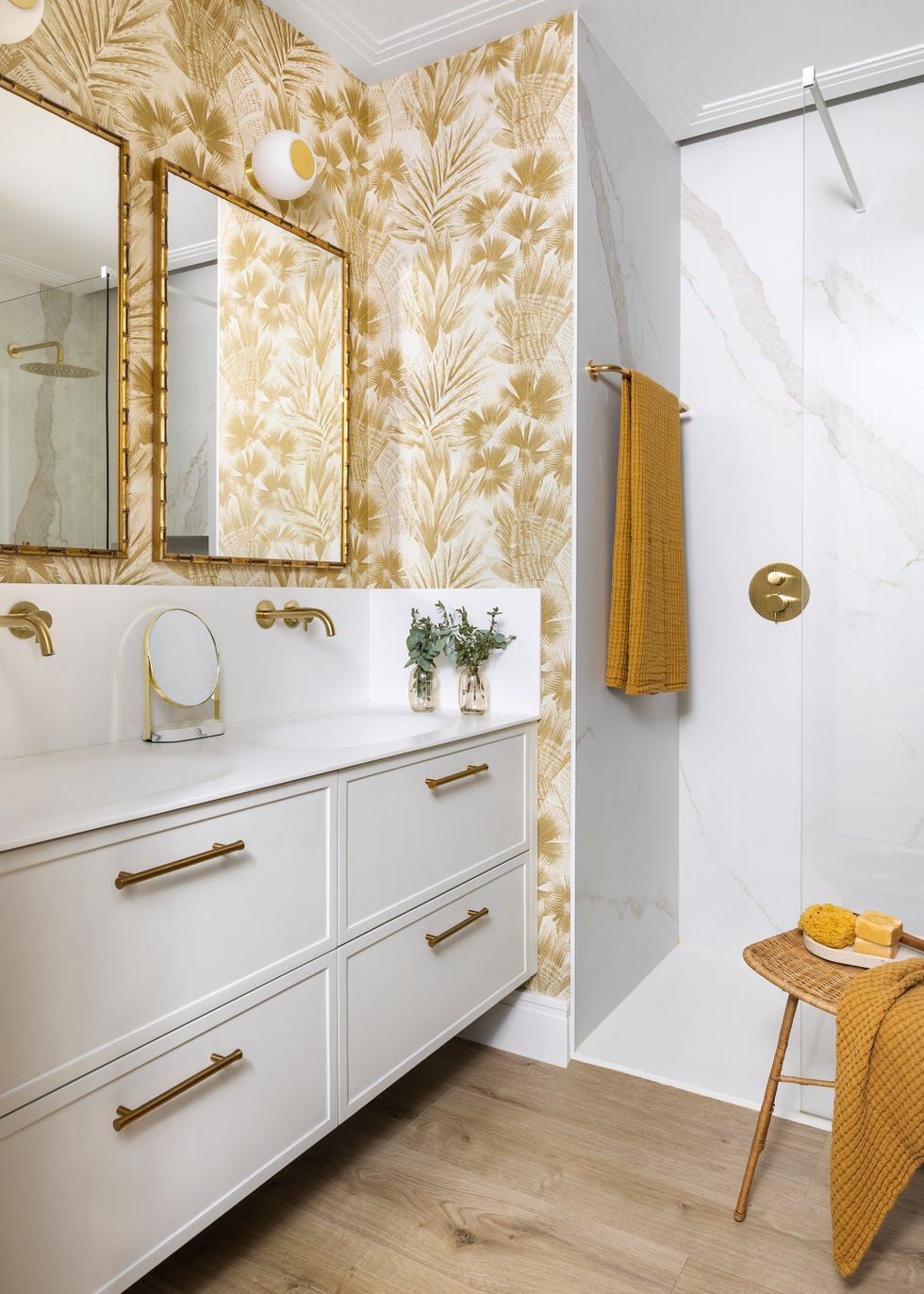 baño con mueble de lavabo volado y papel pintado con motivos dorados de hojas