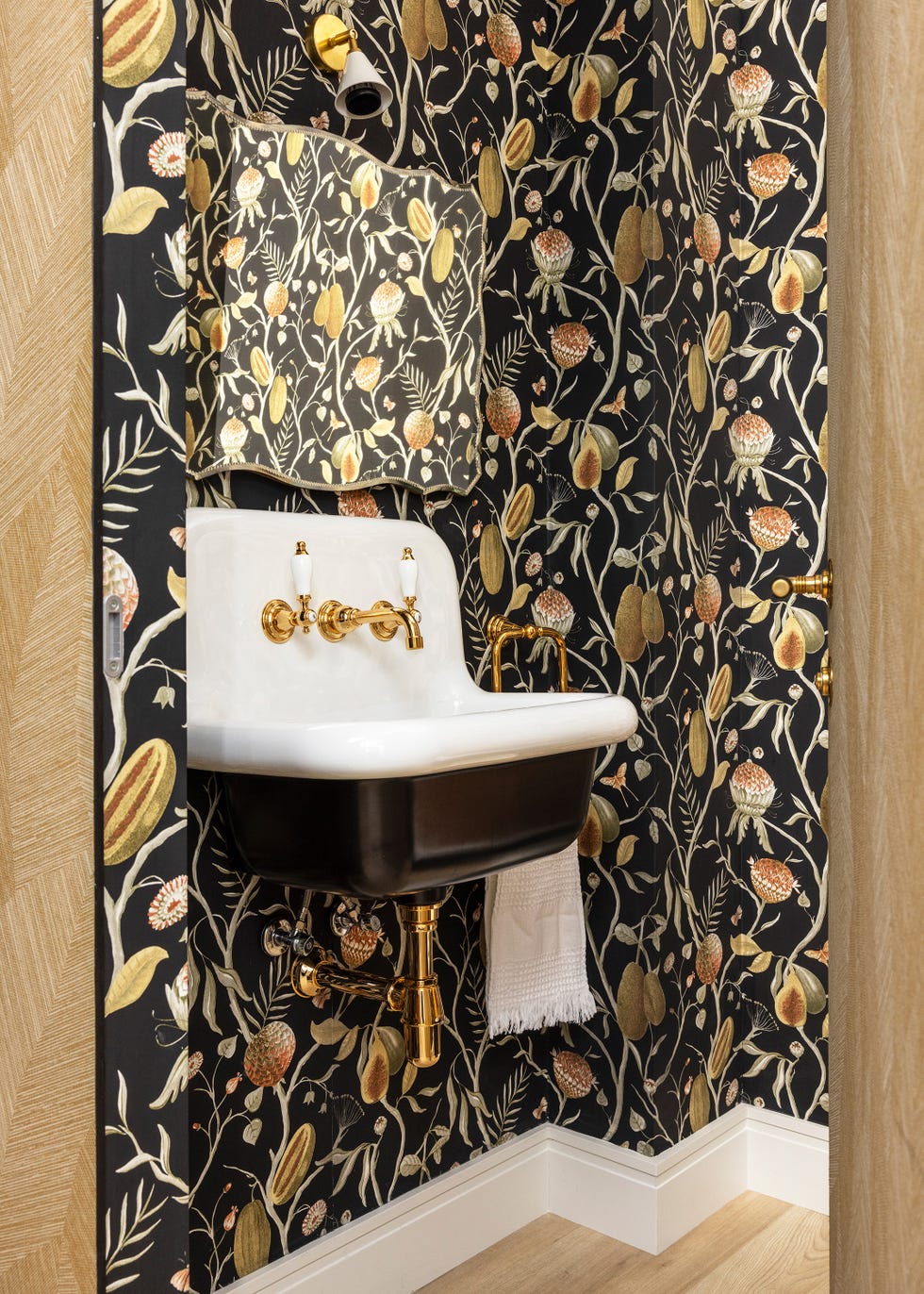 aseo con lavabo retro en negro y papel pintado con motivos botánicos amarillos sobre fondo negro