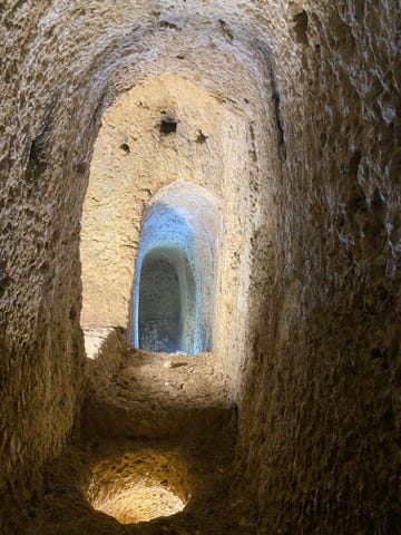 earthen tunnel and a circular hole in the floor with light shining through