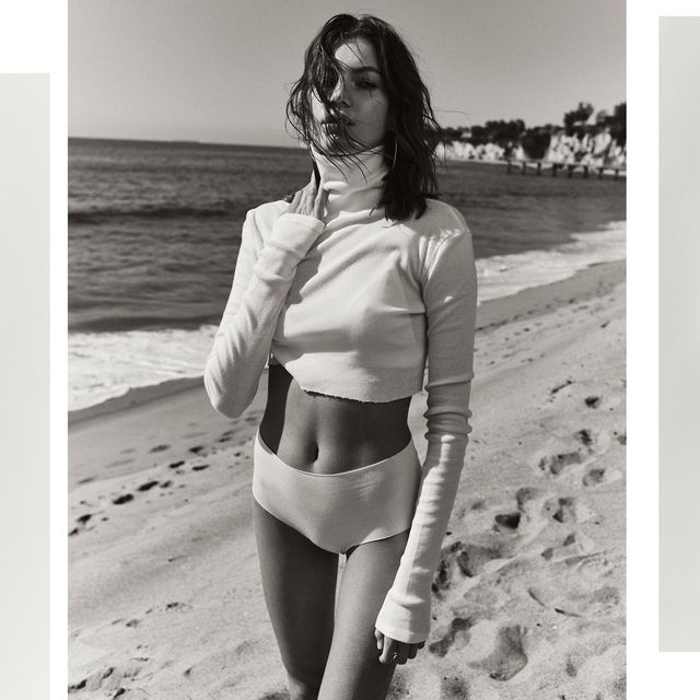 a model for essentials brand eterne designed by chloe bartoli wears a cropped turtleneck and romper in neutral tones in front of backdrops and on a beach