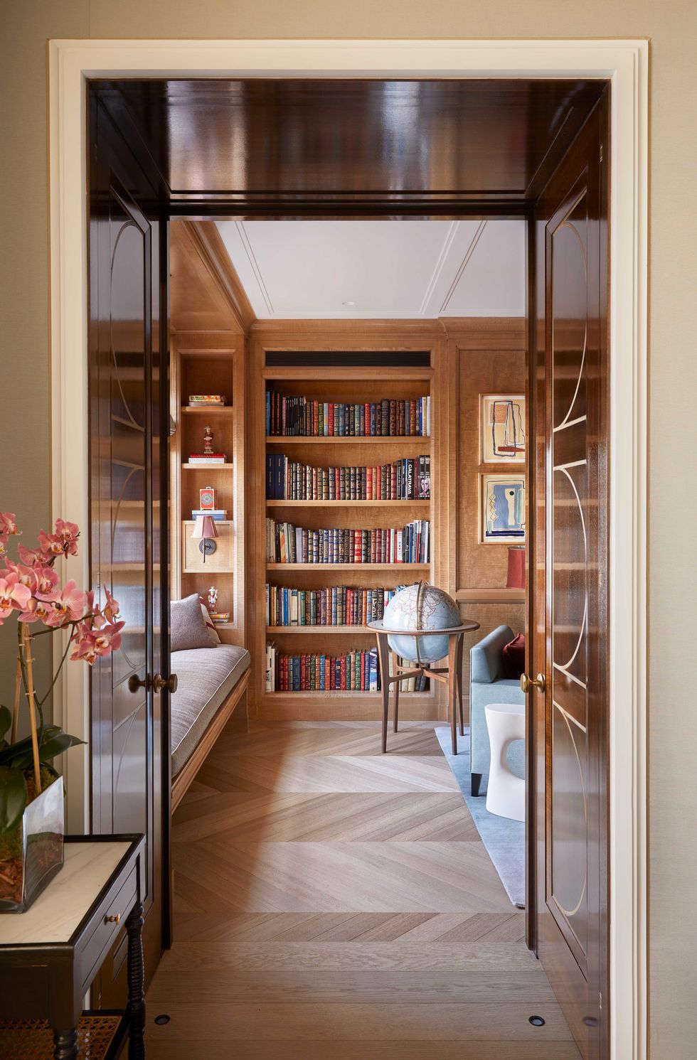 view through a door into a library with a bookcase globe and parquet floors