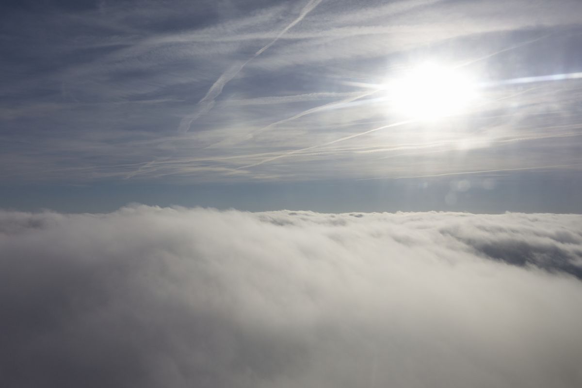 teppe av skyer i nederste halvdel av bildet, med solen i øverste høyre hjørne