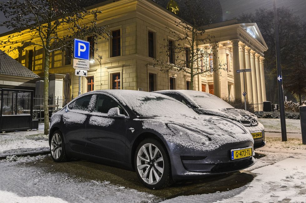 electric cars charging at an electric vehicle charging station during a cold winter night in the city center of zwolle the bmw i3 and tesla model 3 are covered in a thin layer of snow
