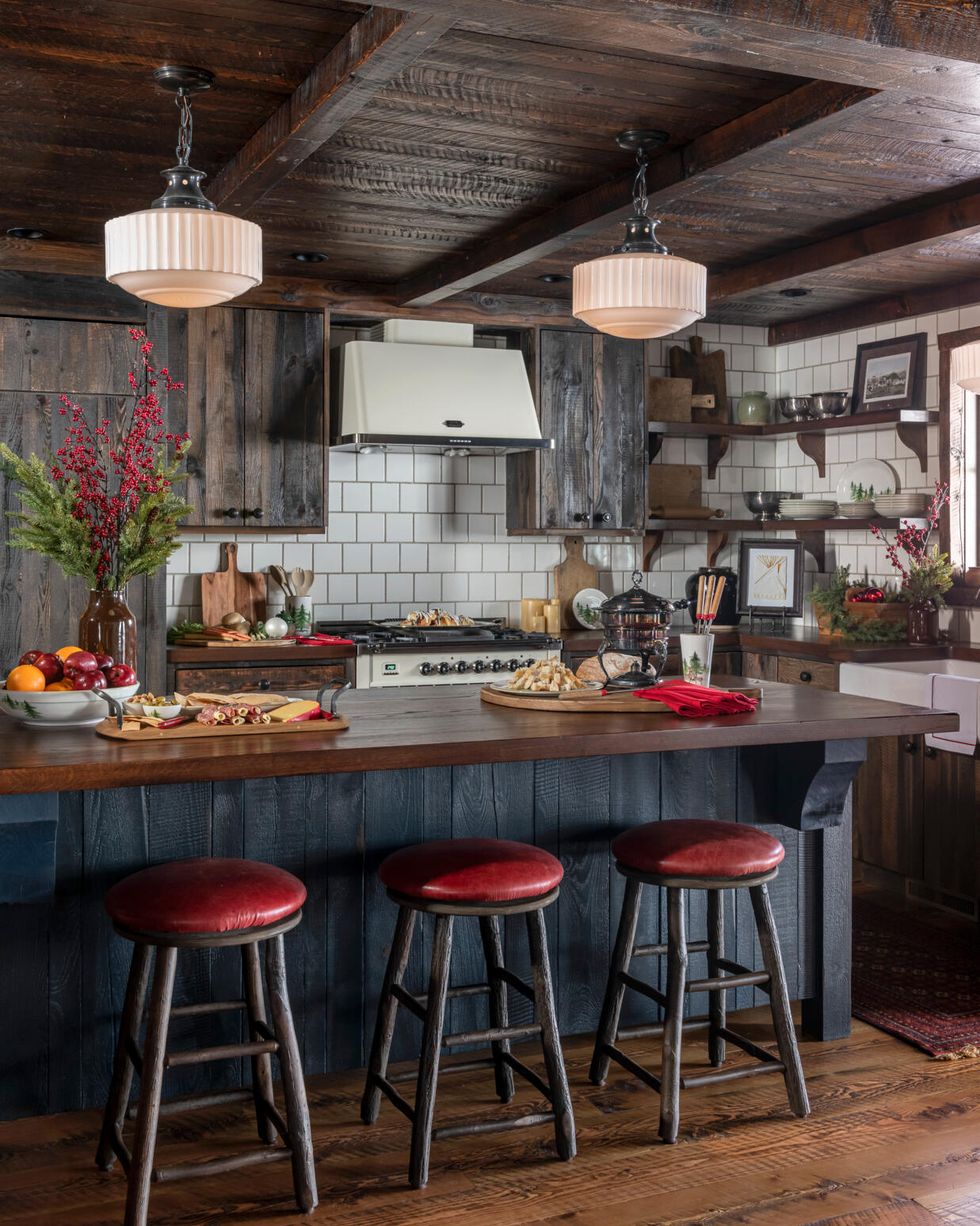 a corner of a farmhouse kitchen with a dark blue island and red topped counterstools