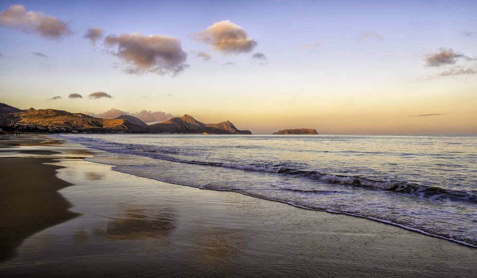 Praia de Puerto Santo capturada com ondas suaves ao pôr do sol