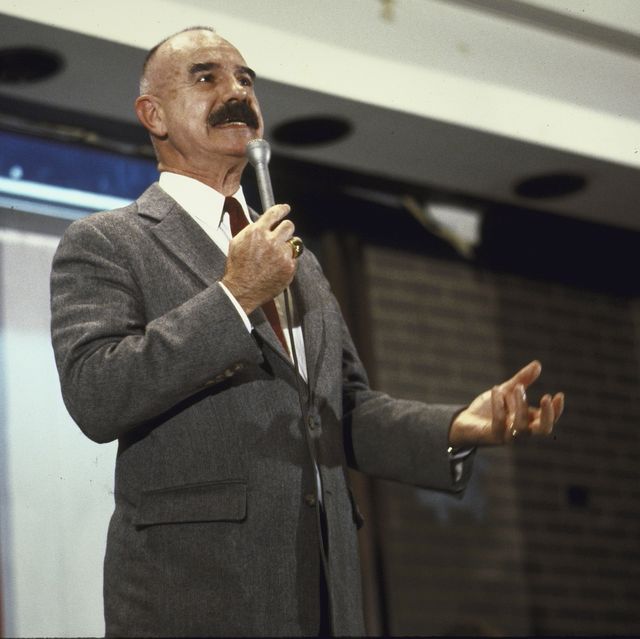 g gordon liddy speaking into a microphone while looking off camera