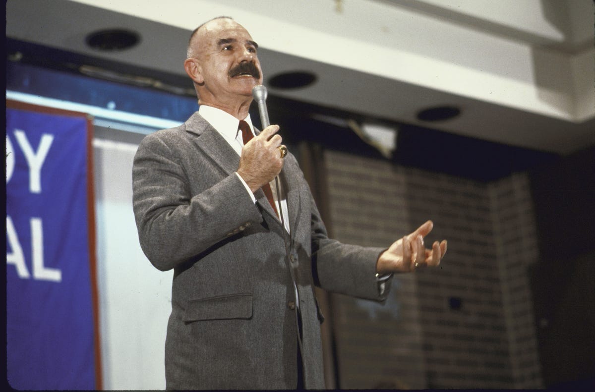 g gordon liddy speaking into a microphone while looking off camera