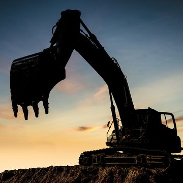excavator at a construction site against the setting sun
