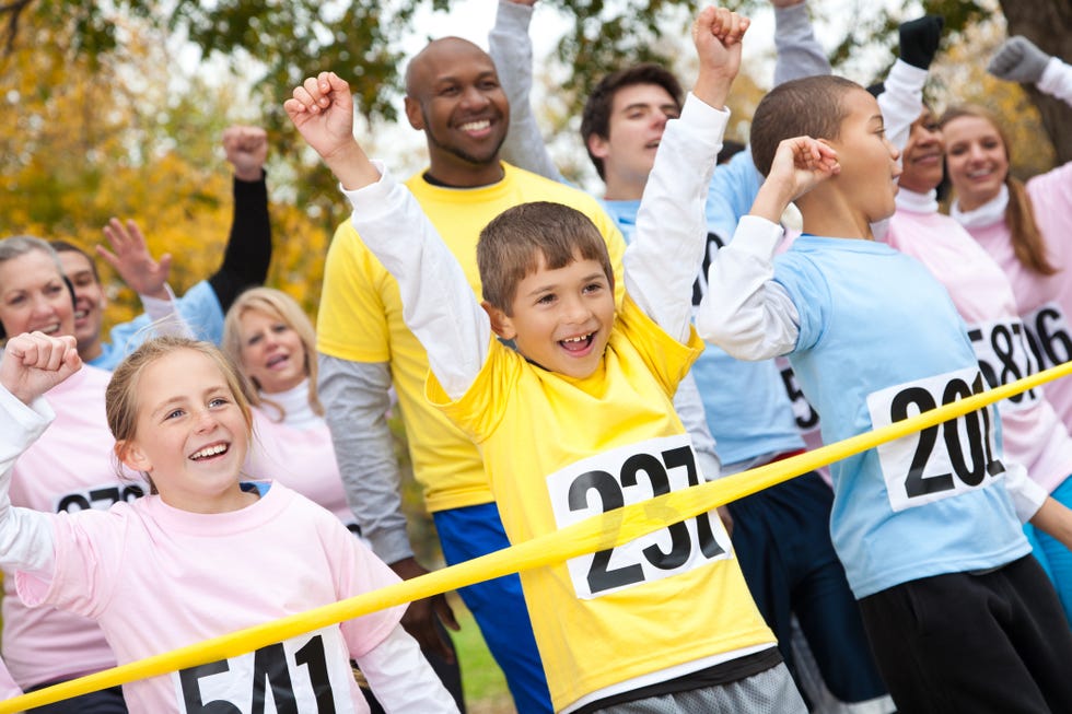 Excited children and adults happily crossing a race finish line