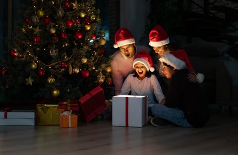 familia abriendo regalo en casa bajo el árbol