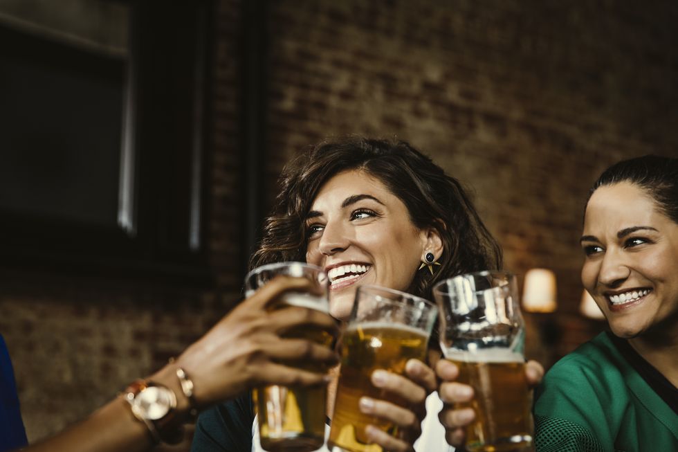 excited female sports fans celebrating in bar at pub