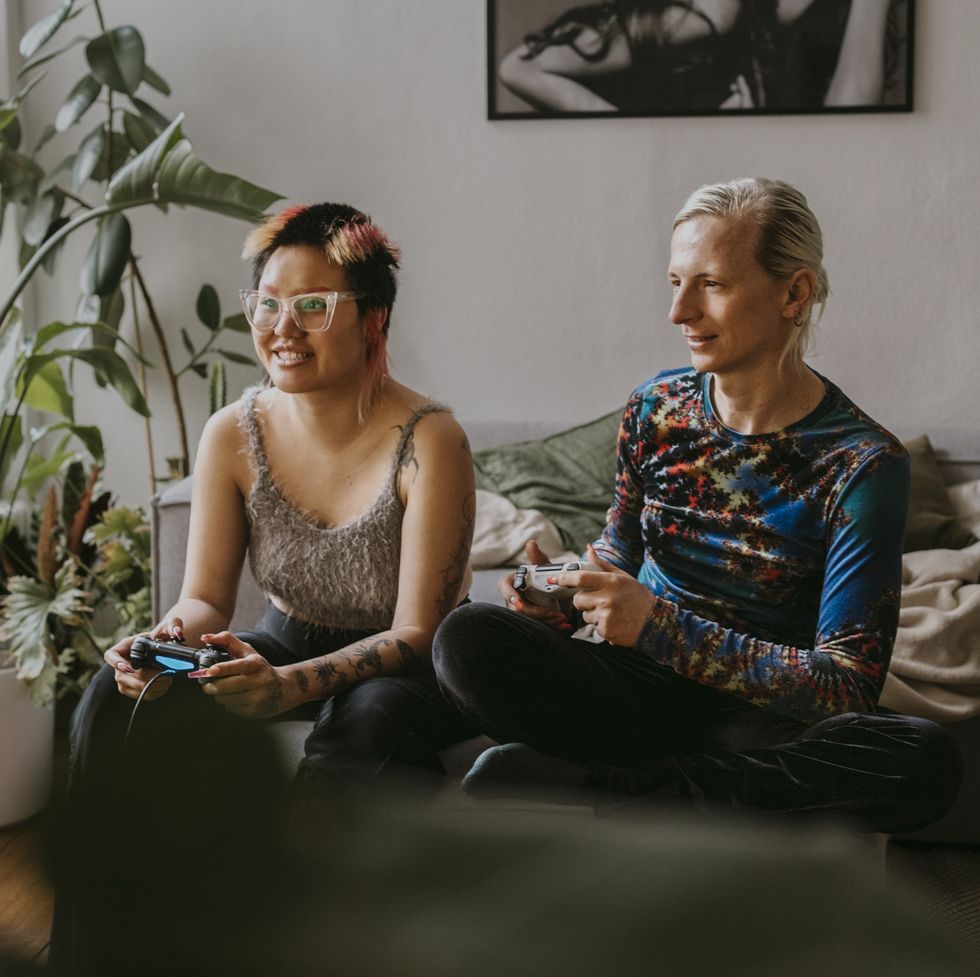 excited gay couple playing video game sitting at home