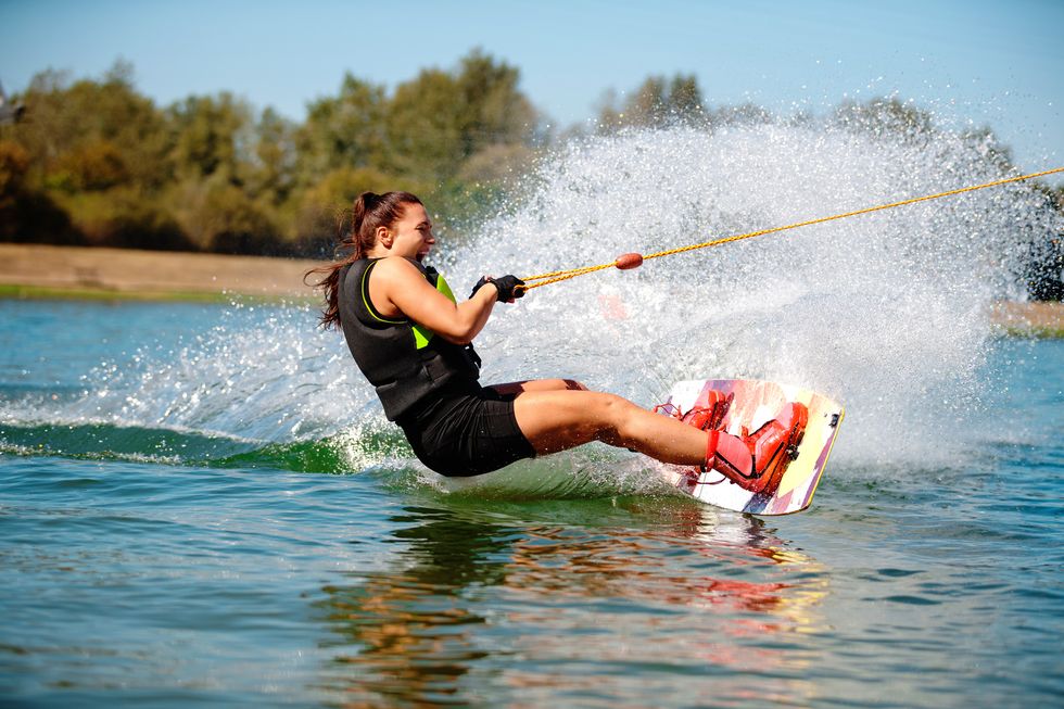 excited young woman riding wakeboard