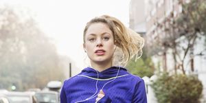 young woman jogging down the street with headphones on