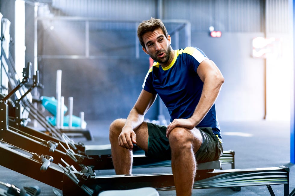 exhausted male sitting on rowing machine