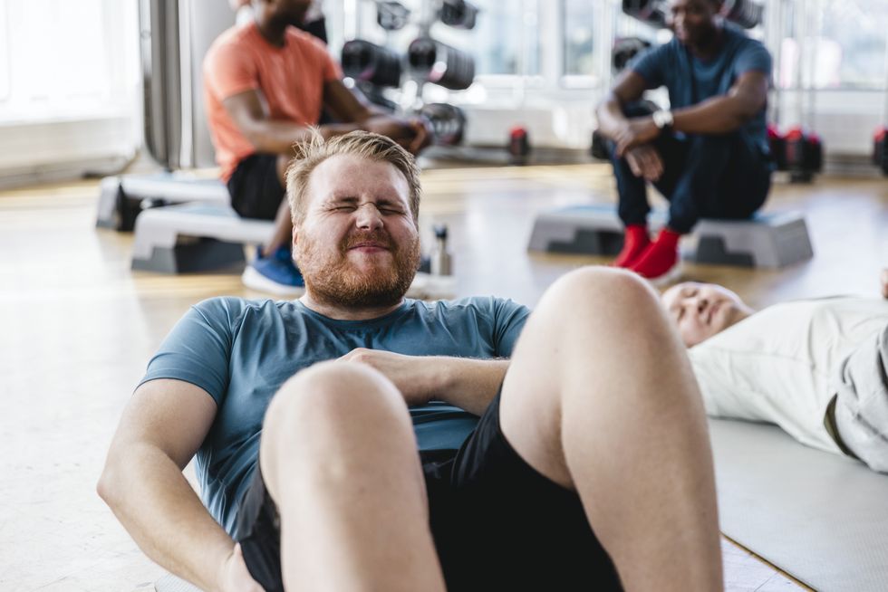 exhausted man taking break after exercise class in gym