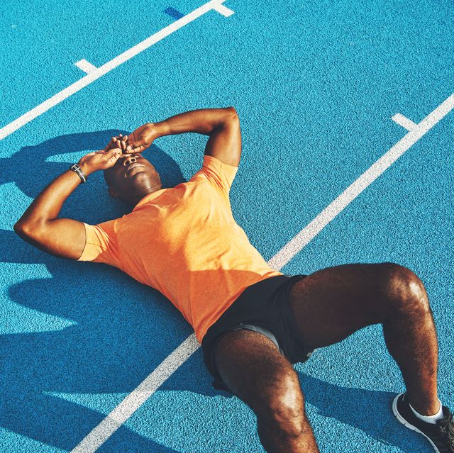exhausted young athletic lying on a running track after training