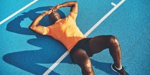 exhausted young athletic lying on a running track after training