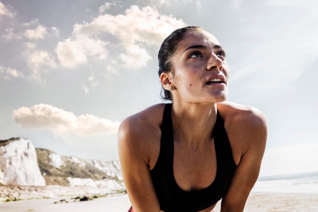 exhausted young female runner taking a break on beach