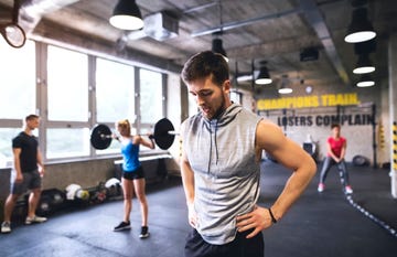 exhausted young man in gym having a break