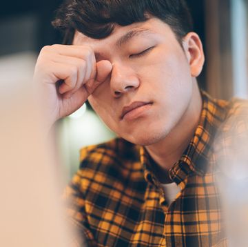 exhausted young man rubbing eyes in cafe