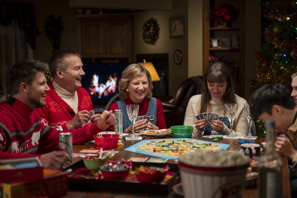 Robbie Amell, Michael Hitchcock, Kathryn Greenwood und Leighton Meester sitzen zu Weihnachten im Film „Exmas“ an einem Tisch und spielen ein Brettspiel