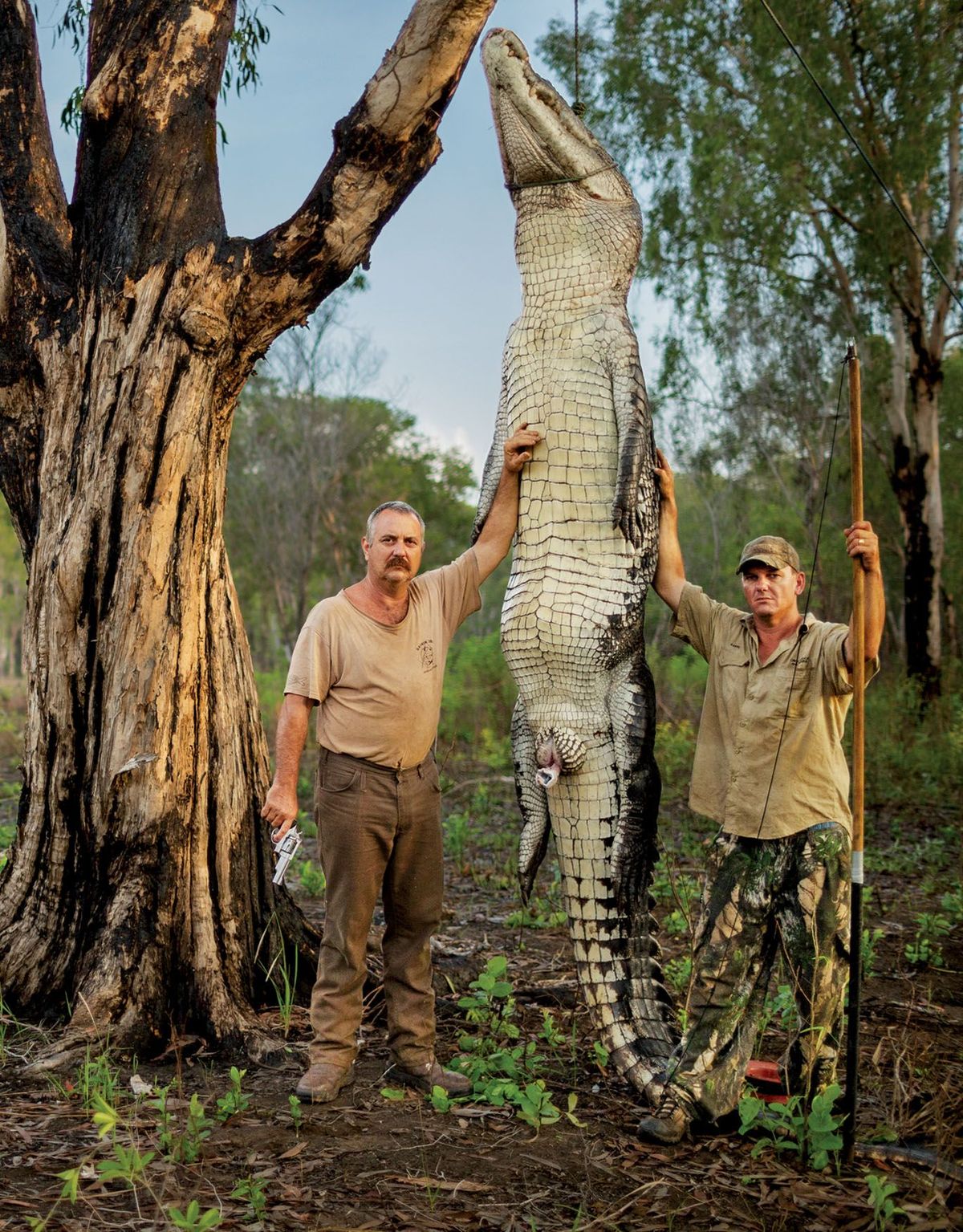 Roger Matthews links en Aaron Rodwel staan naast een 45 meter lange en 450 kilogram zware zeekrokodil dat legaal gevangen en gedood is in het Northern Territory in Australi