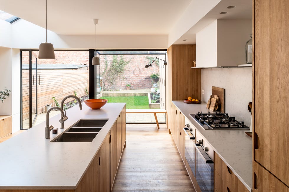 cocina de madera con isla central y encimera de mármol a juego con el frente de cocina